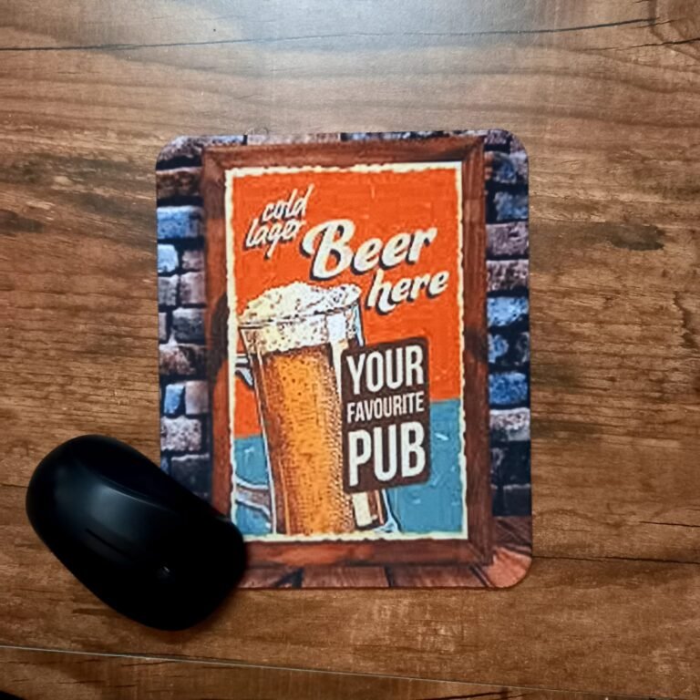 "A mousepad with a vintage-style printed beer sign that says 'Cold Lager Beer Here' and 'Your Favourite Pub,' placed on a wooden table with a black mouse next to it."